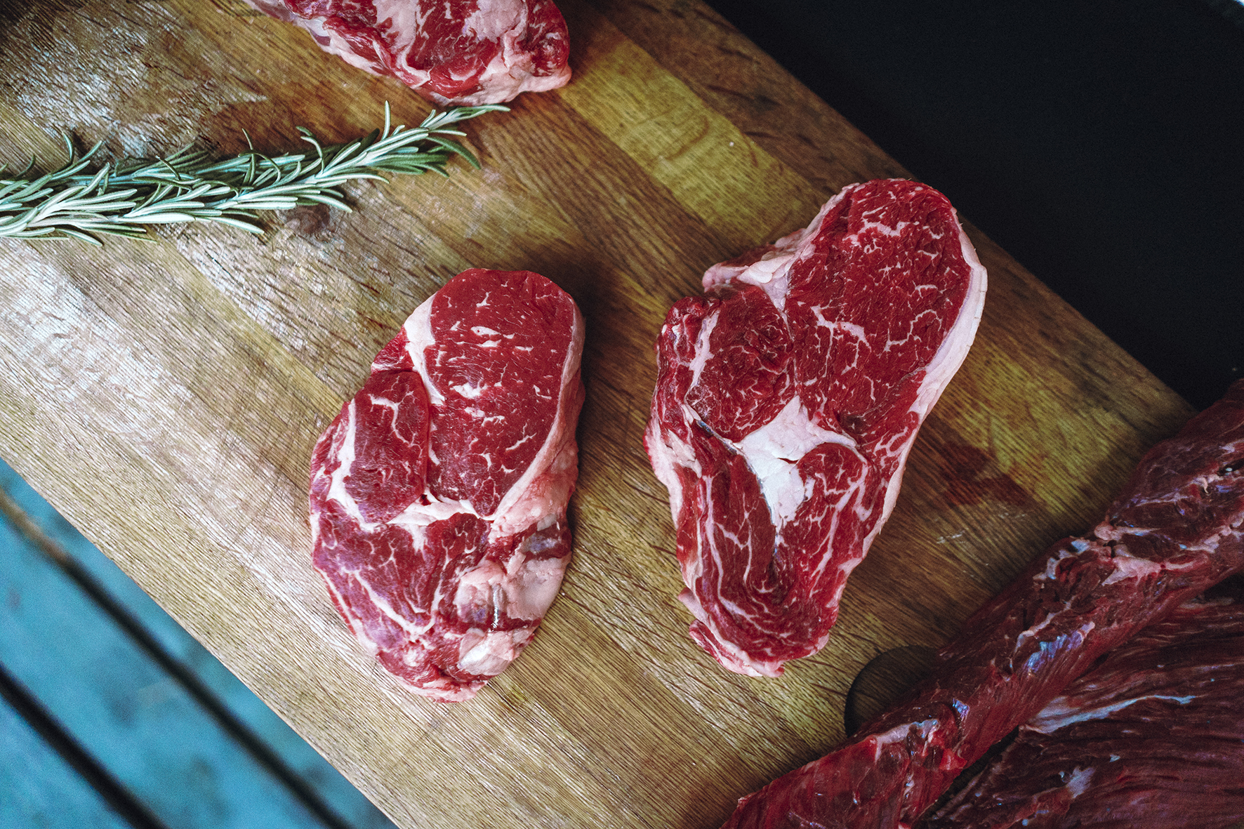 Process of cooking meat on grill close-up. Fresh tenderloin of meat on bone. Barbecue and picnic. Fresh cuts of meat close-up dark background. Cinematic stylish color grading with noise and grain.