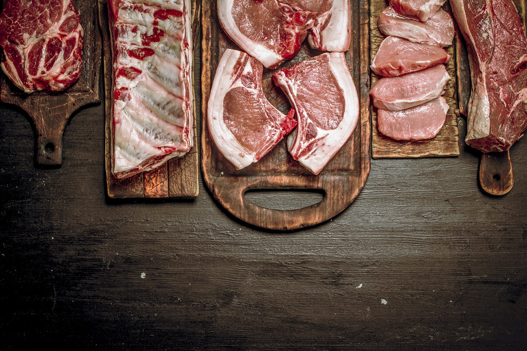 Different types of raw pork meat and beef. On the black chalkboard.